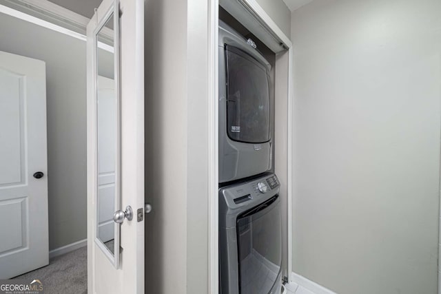 laundry area with carpet floors, baseboards, and stacked washer / drying machine