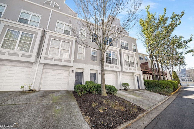 multi unit property with a garage, brick siding, concrete driveway, a residential view, and stucco siding