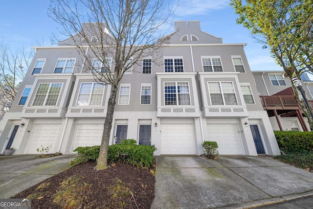 multi unit property with brick siding, driveway, an attached garage, and stucco siding