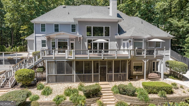 back of property featuring stairway, stucco siding, a shingled roof, and a chimney