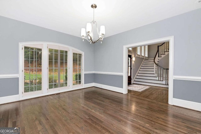 unfurnished dining area with stairs, an inviting chandelier, wood finished floors, and baseboards