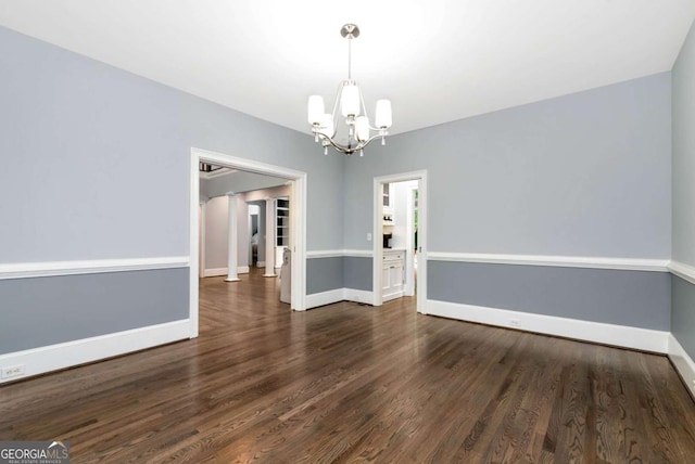 empty room featuring an inviting chandelier, baseboards, and dark wood-style flooring