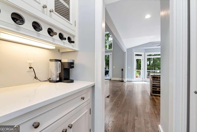 bar featuring beverage cooler, dark wood finished floors, baseboards, and lofted ceiling