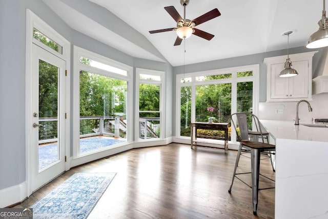 unfurnished sunroom with wood finished floors, a wealth of natural light, lofted ceiling, and a sink
