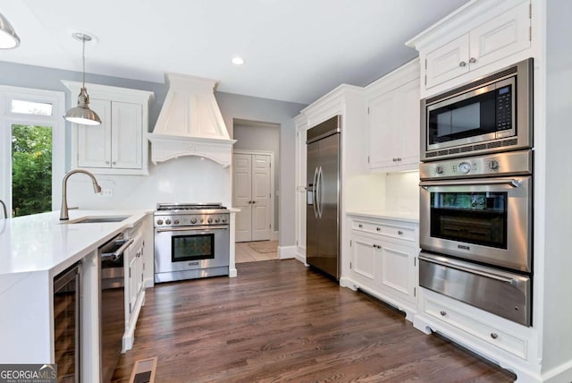 kitchen with a warming drawer, a sink, light countertops, built in appliances, and custom exhaust hood