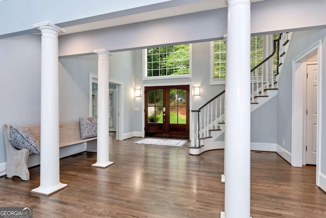 foyer featuring stairs, decorative columns, wood finished floors, and baseboards