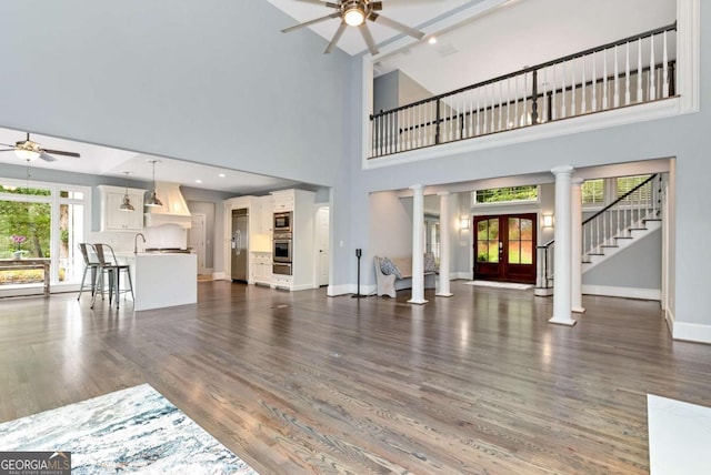 living room featuring dark wood-type flooring, baseboards, recessed lighting, a ceiling fan, and ornate columns