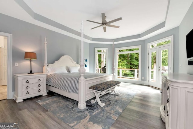 bedroom with ceiling fan, a tray ceiling, access to exterior, french doors, and wood finished floors