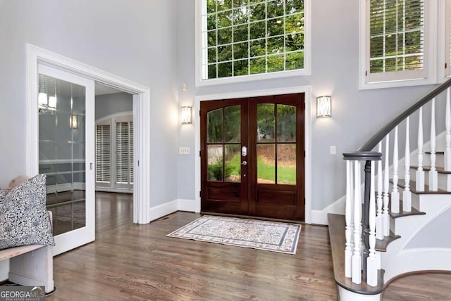 entrance foyer featuring stairway, baseboards, a towering ceiling, french doors, and wood finished floors