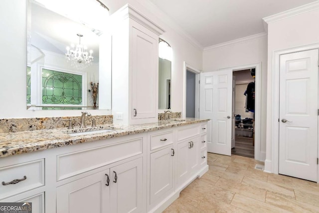 bathroom with a sink, double vanity, a notable chandelier, and ornamental molding