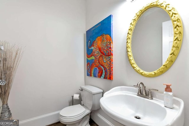 bathroom with toilet, baseboards, and a sink