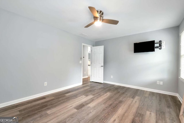 empty room featuring baseboards, ceiling fan, and dark wood-style flooring