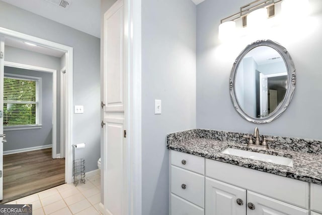 bathroom featuring visible vents, baseboards, toilet, tile patterned floors, and vanity