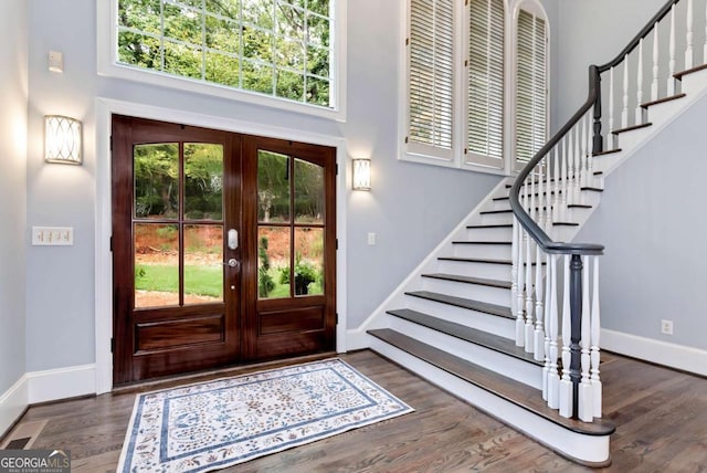 foyer with baseboards, stairs, wood finished floors, and a high ceiling
