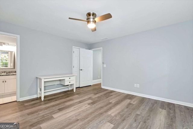 unfurnished bedroom with ceiling fan, light wood-style flooring, connected bathroom, and baseboards