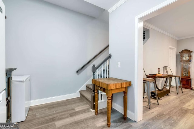 stairway with baseboards, wood finished floors, and crown molding