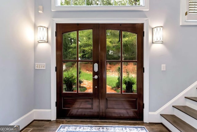 doorway to outside with wood finished floors, baseboards, and stairs