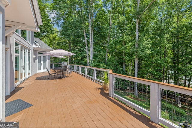 wooden terrace featuring french doors and outdoor dining area