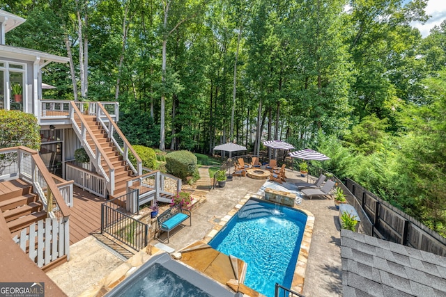 view of swimming pool featuring a wooden deck, an outdoor fire pit, a fenced in pool, a fenced backyard, and stairs