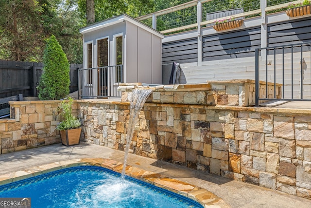 view of swimming pool featuring fence and an outbuilding