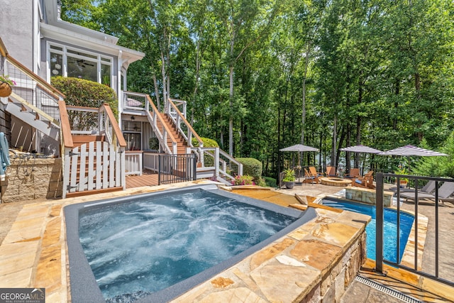 pool with a patio, an in ground hot tub, a deck, ceiling fan, and stairway