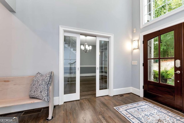 entrance foyer with a chandelier, dark wood finished floors, french doors, and baseboards