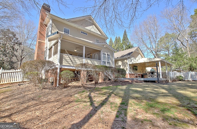 back of property featuring a lawn, a chimney, fence, and a wooden deck