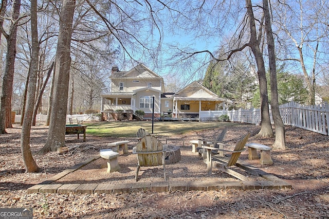 back of property with an outdoor fire pit, a chimney, and fence