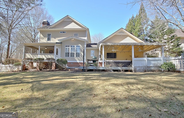 back of property featuring a ceiling fan, fence, a chimney, and a lawn