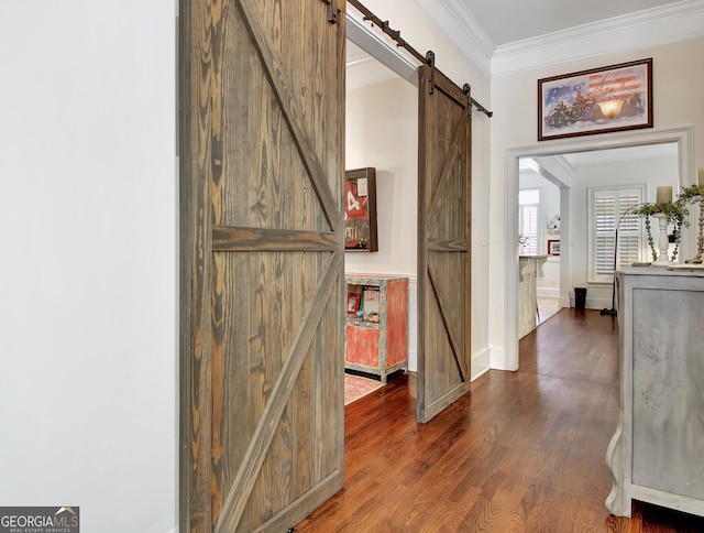 corridor featuring ornamental molding, a barn door, and wood finished floors