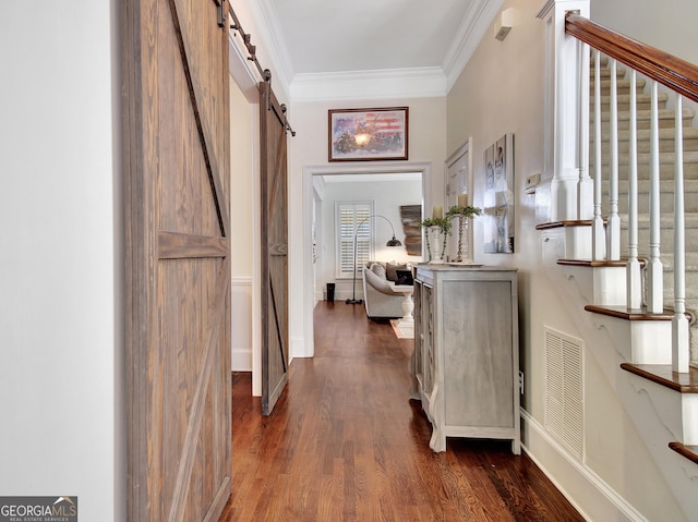 corridor featuring ornamental molding, a barn door, dark wood finished floors, and visible vents