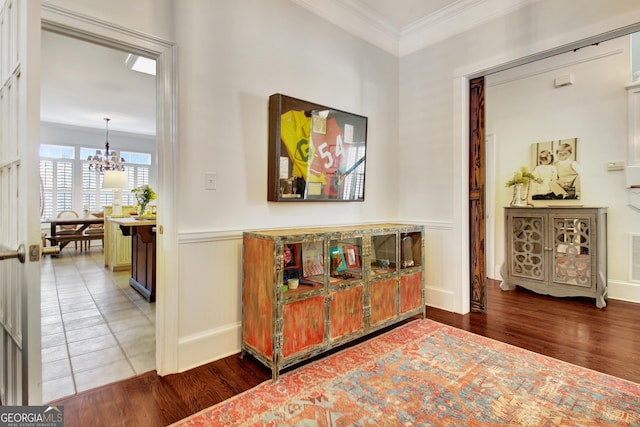 hallway featuring an inviting chandelier, wainscoting, crown molding, and wood finished floors