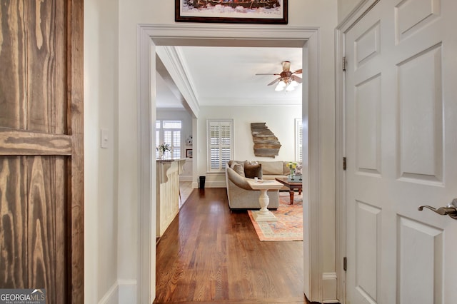 hall with ornamental molding, baseboards, and dark wood-style floors