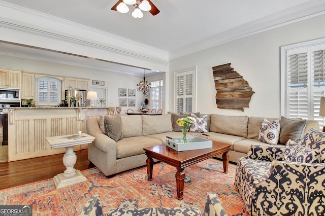 living room with light wood-style floors, ornamental molding, and ceiling fan with notable chandelier