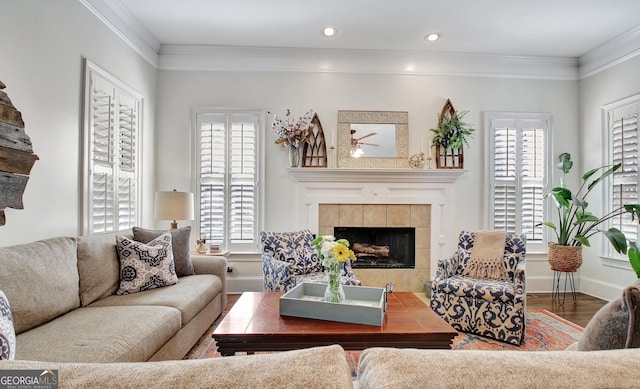 living room with crown molding, a tile fireplace, wood finished floors, and a healthy amount of sunlight