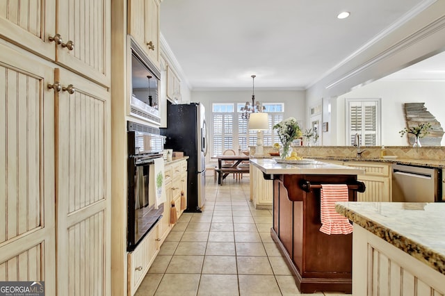 kitchen with stainless steel appliances, cream cabinets, ornamental molding, light tile patterned flooring, and a sink