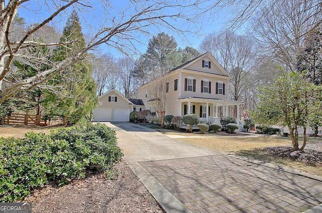 view of front facade with a garage, covered porch, fence, and an outdoor structure