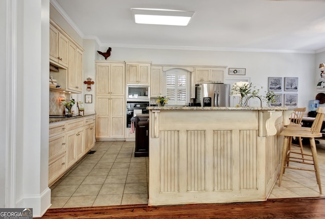 kitchen featuring appliances with stainless steel finishes, cream cabinetry, light tile patterned flooring, and crown molding