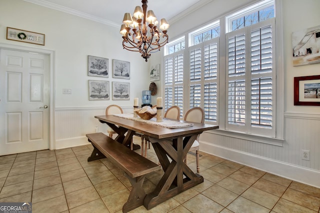 dining room featuring light tile patterned floors, ornamental molding, and wainscoting