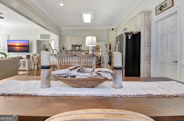 kitchen featuring cream cabinetry, backsplash, freestanding refrigerator, and crown molding