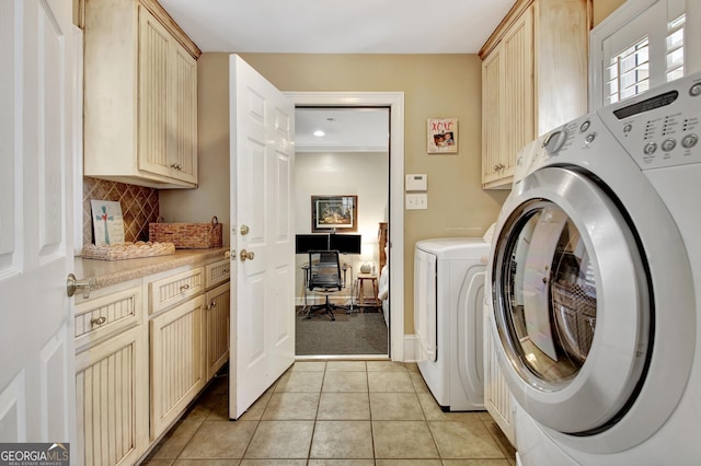 clothes washing area with cabinet space, light tile patterned floors, and washer and clothes dryer