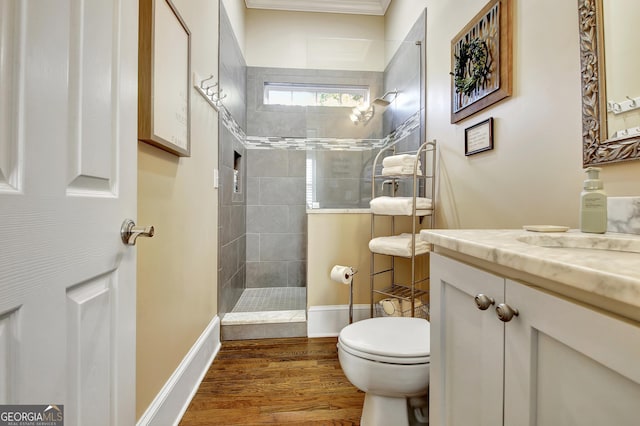 bathroom featuring toilet, vanity, wood finished floors, baseboards, and walk in shower