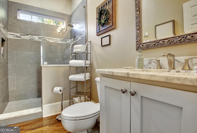 bathroom featuring toilet, walk in shower, wood finished floors, and vanity