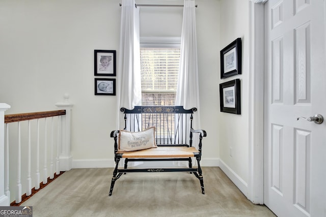 sitting room with carpet, baseboards, and an upstairs landing