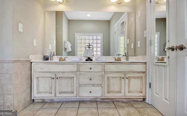 full bath featuring double vanity, tile patterned flooring, tile walls, and a sink