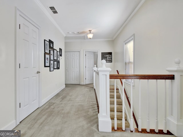 hall with visible vents, ornamental molding, carpet flooring, an upstairs landing, and baseboards