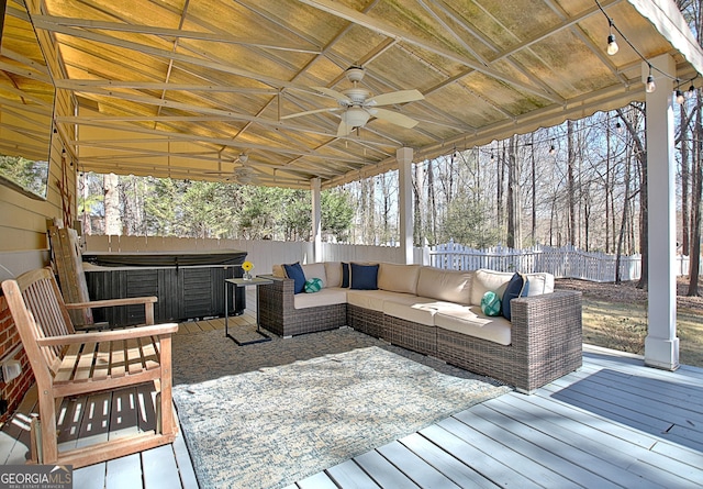 wooden terrace with a hot tub, a fenced backyard, outdoor lounge area, and a ceiling fan