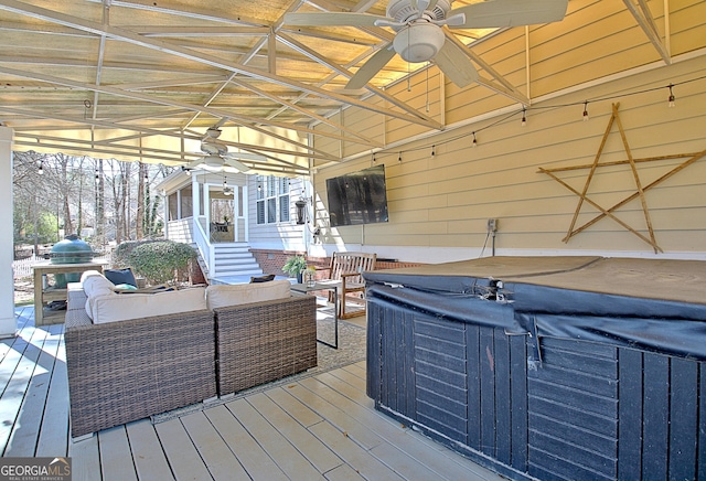 wooden terrace with a ceiling fan, outdoor lounge area, and a hot tub