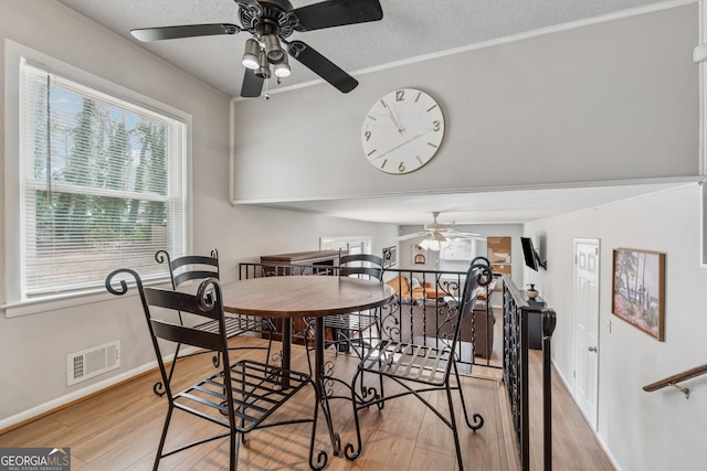 dining area with visible vents, ornamental molding, a textured ceiling, wood finished floors, and baseboards