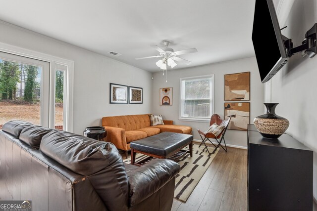 living room with baseboards, light wood-style floors, visible vents, and ceiling fan